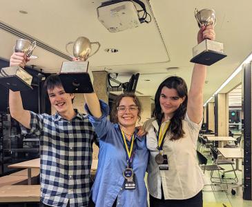 Lachie Doyle holding his Novice Best Speaker trophy, Liv Bishara holding the Australian Intervarsity Debating Championship trophy and Conna Leslie-Keefe holding her Overall Best Speaker trophy